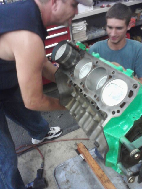 1989 Ford Bronco - Mechanics work on an engine block, installing pistons into the cylinders.
