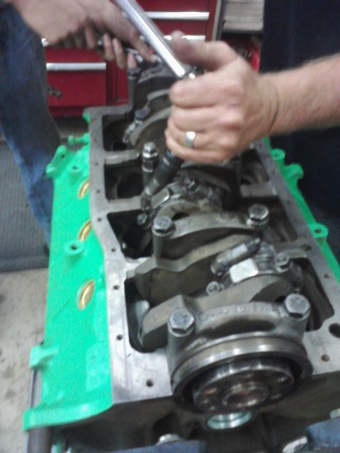 1989 Ford Bronco - Mechanic uses a torque wrench on an engine block's crankshaft assembly.