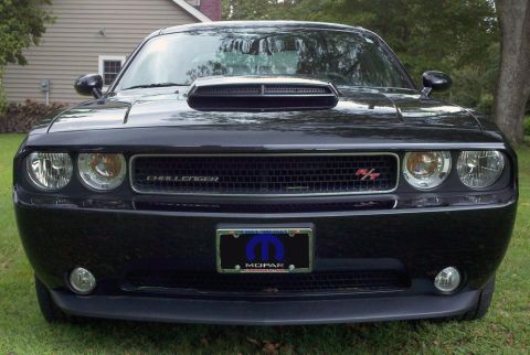 2011 Dodge Challenger - Front view of a black 2011 Dodge Challenger with a prominent hood scoop and grille.