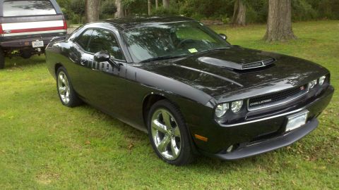 2011 Dodge Challenger - A black 2011 Dodge Challenger is parked on a grassy lawn next to a pickup truck.