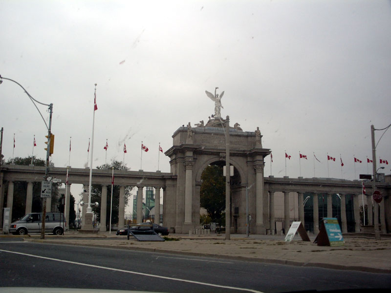 Monument with many Canadian flags and two cars parked in front