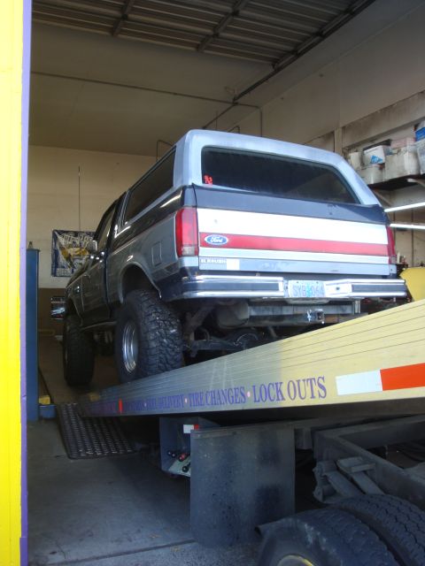 1989 Ford Bronco - Ford Bronco being loaded onto a tow truck, showing its rear and side profile.