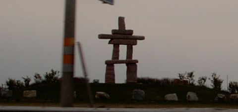 1999 Ford Crown Victoria - An Inukshuk statue stands on a hill under an overcast sky, with a utility pole to the left.