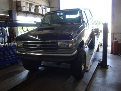 1989 Ford Bronco - This dark blue 1989 Ford Bronco is positioned on a car lift inside a garage.
