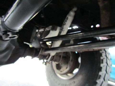 1984 Ford Bronco - Close-up of vehicle undercarriage, focusing on suspension and tire.