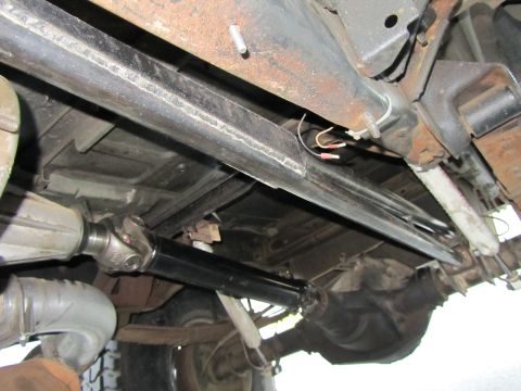 1984 Ford Bronco - The underside of a vehicle is shown, focusing on the drivetrain and frame elements.
