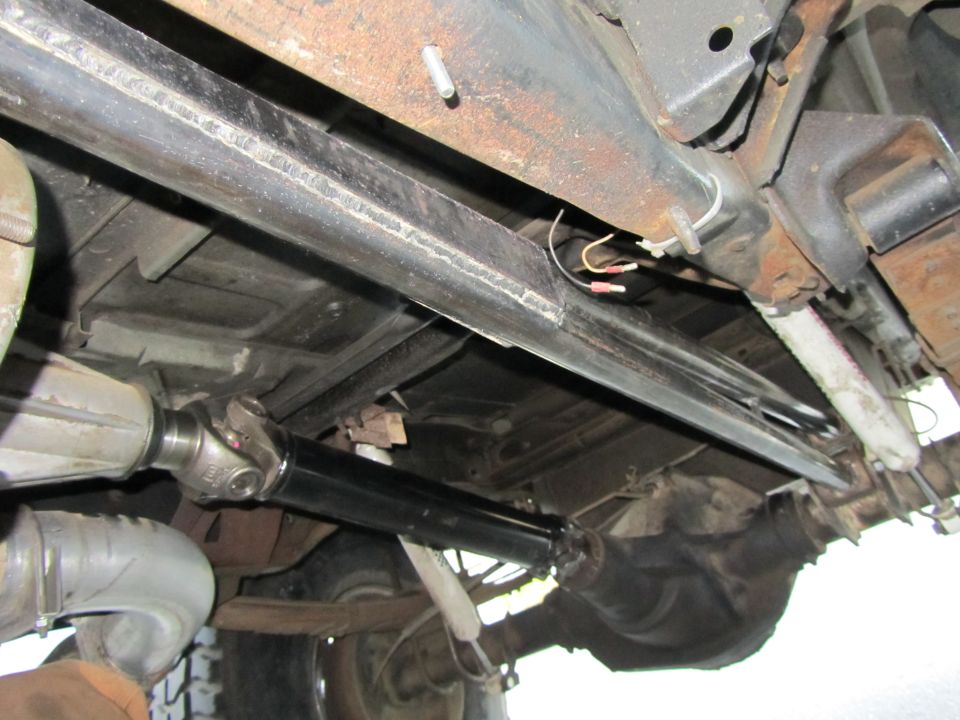 Underside of vehicle showing driveshaft, differential, and frame components