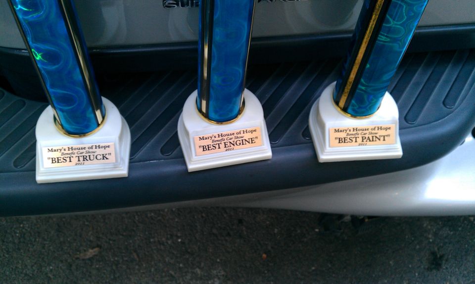 Three trophies on the rear bumper of a 2002 Ford F-150. Trophies are for 'Best Truck', 'Best Engine', and 'Best Paint'