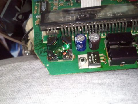 1994 Ford Bronco - This electronic circuit board features various components including capacitors and a voltage regulator, with a small gauge visible.