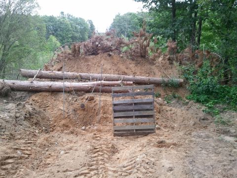 1985 Ford F-150 - A construction scene shows logs and a pallet against a dirt embankment with tire tracks.
