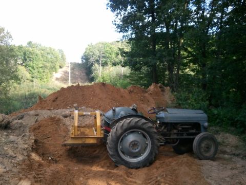 1985 Ford F-150 - Tractor with front loader working in a dirt pile.