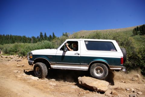 1996 Ford Bronco - This 1996 Ford Bronco navigates a challenging off-road course, kicking up dust on the rocky terrain.