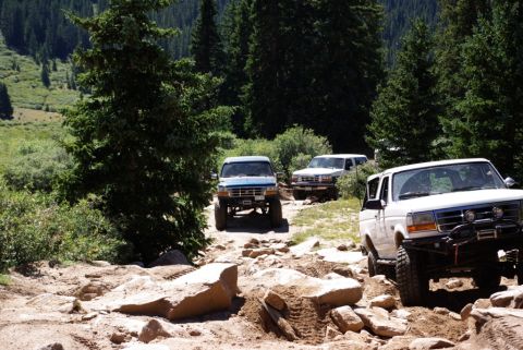 1996 Ford Bronco - Three 1996 Ford Broncos navigate a challenging rocky trail in the mountains.