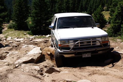 1996 Ford Bronco - This white Ford Bronco is shown off-roading on a challenging, rocky path.