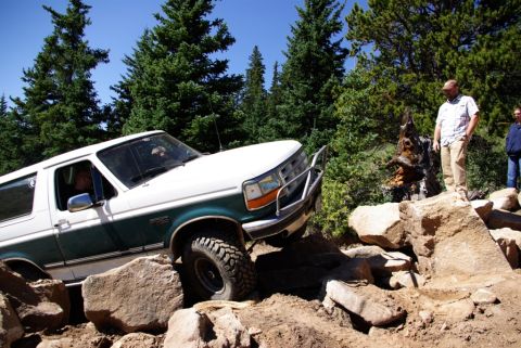 1996 Ford Bronco - A 1996 Ford Bronco tackles a challenging off-road course with onlookers observing.