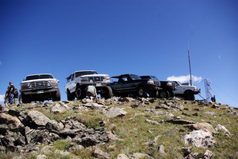 1996 Ford Bronco - Several SUVs are parked on a rocky incline with a clear blue sky above.