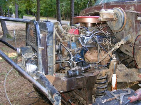 1978 Ford Bronco - The engine bay of a heavily modified and rusty vehicle, showing a V8 engine and exposed components.
