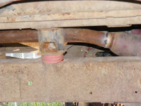 1978 Ford Bronco - Close-up view of the undercarriage, showing a rusty frame and exhaust system with a red bumper stop.
