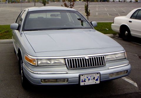 1999 Ford Crown Victoria - A silver Mercury Grand Marquis is parked in a lot, with another vehicle in the background.