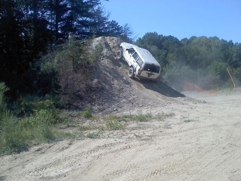 1989 Ford Bronco - A white SUV navigates a challenging dirt incline during an off-road event.