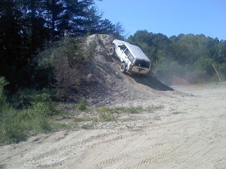 White SUV climbing a steep dirt hill, kicking up dust