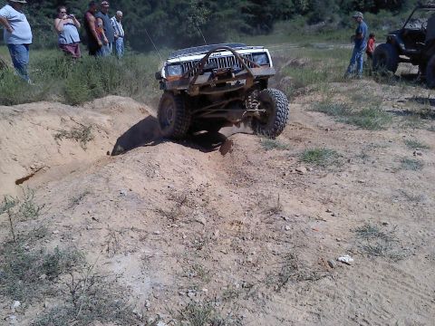 1989 Ford Bronco - A modified Jeep navigates a challenging off-road course with spectators observing the action.