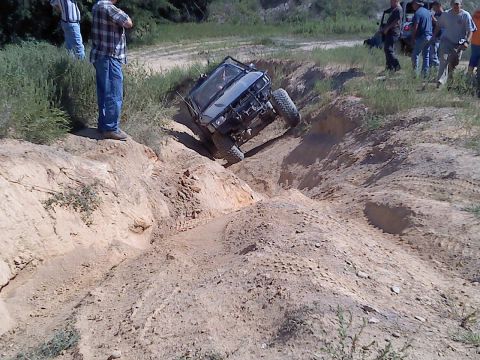 1989 Ford Bronco - A modified SUV navigates a challenging off-road course with spectators watching.