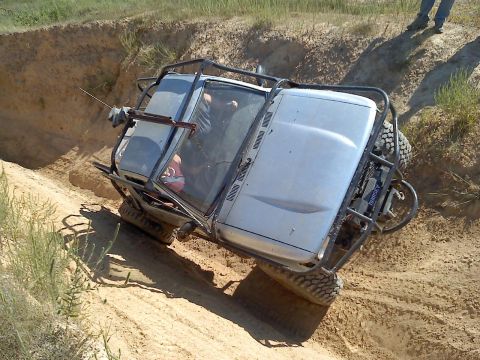 1989 Ford Bronco - An off-road vehicle navigates a steep dirt incline, its roll cage clearly visible.