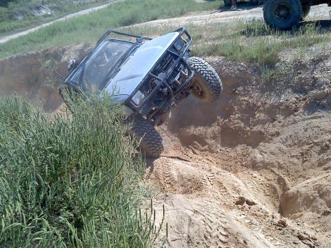 1989 Ford Bronco - An off-road vehicle navigates a challenging dirt incline during an outdoor event.