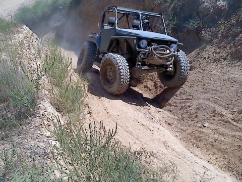 1989 Ford Bronco - An off-road vehicle navigates a steep, dusty incline on a trail.