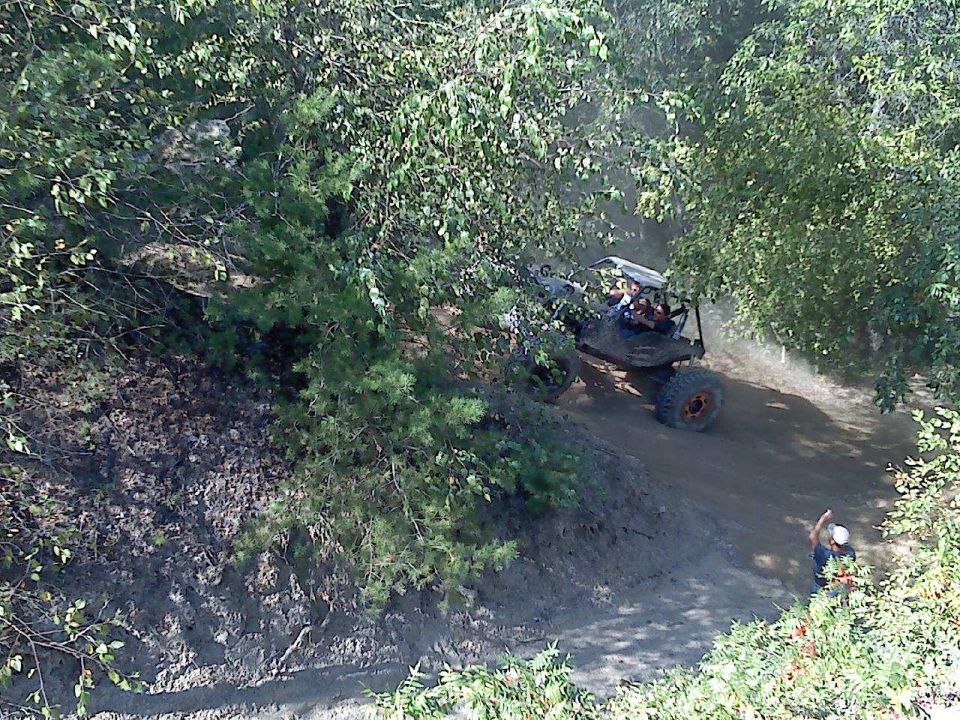 Off-road buggy with large tires navigates a dusty trail