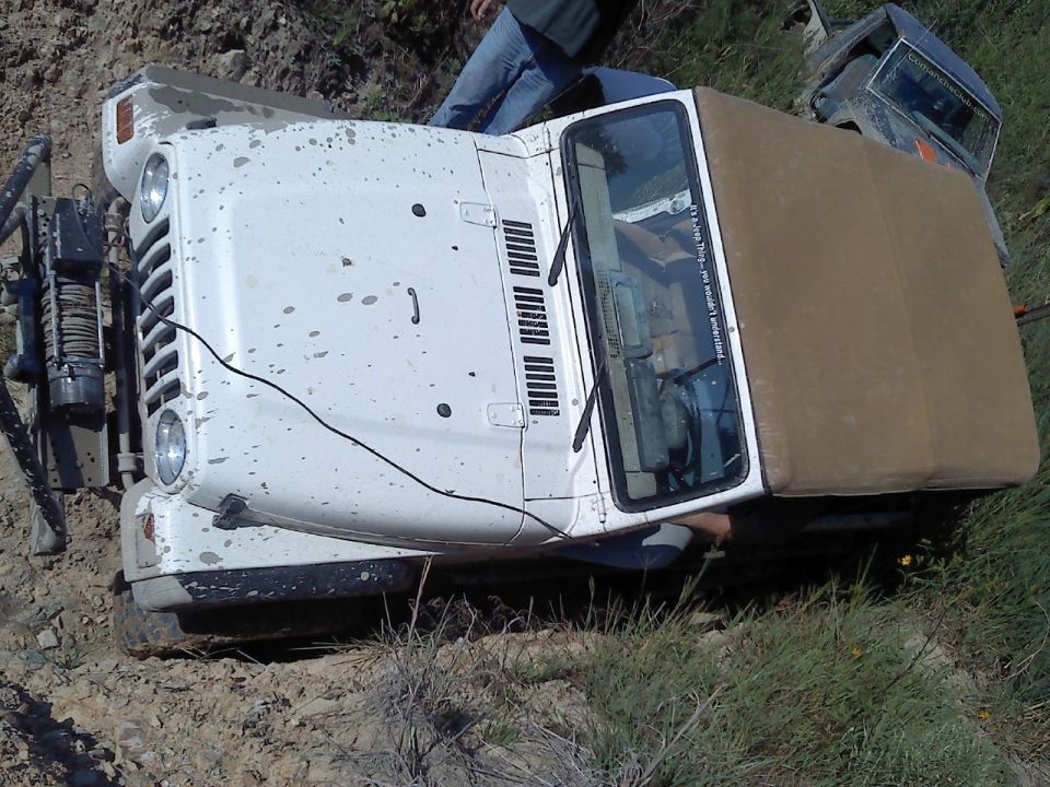 White Jeep Wrangler stuck on a dirt hill with another vehicle behind it