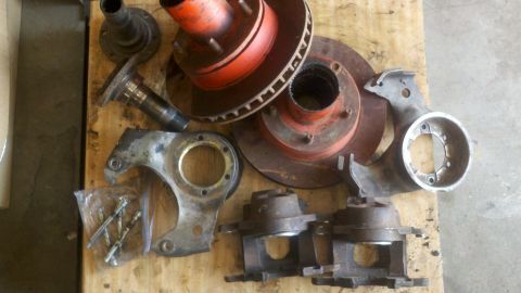 1970 Ford Bronco - Various brake parts, including rotors and hubs, are laid out on a wooden surface.