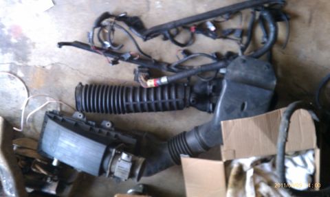 1992 Ford Bronco - Engine air intake components and a wiring harness are laid out on a concrete surface.