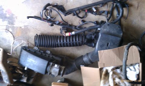 1992 Ford Bronco - Engine air intake components and a wiring harness are laid out on a concrete surface, possibly for repair or replacement.