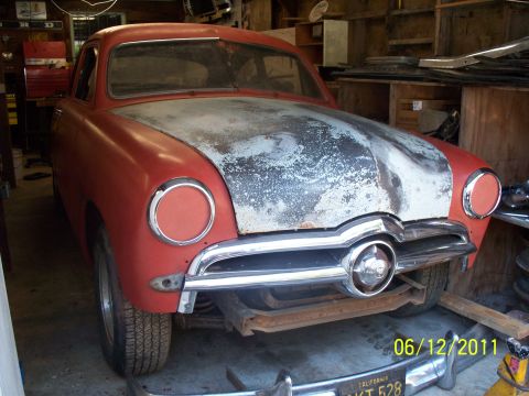 1990 Ford Bronco - This 1950 Ford coupe is in a garage with a primer hood and red body.