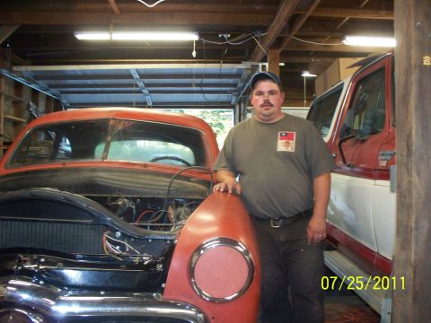 1990 Ford Bronco - A man poses with a vintage car project in a garage, with a truck visible in the background.