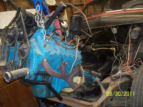 1990 Ford Bronco - Engine assembly being worked on, suspended by a chain hoist in a garage.