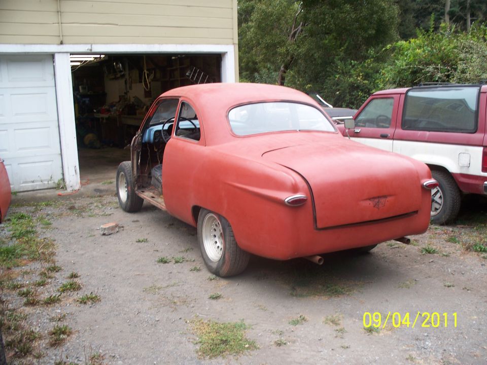 red coupe project car in front of garage, another SUV parked behind it
