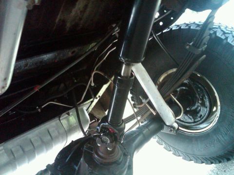 1979 Ford Bronco - Close-up of the driveshaft and suspension system on the underside of a vehicle.