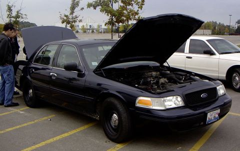1999 Ford Crown Victoria - Dark blue Ford Crown Victoria parked outside with its hood open, a second white Crown Victoria is visible behind it.