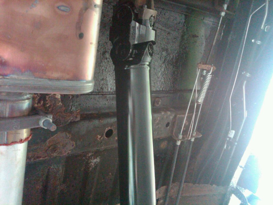 Driveshaft and rusted undercarriage components with cables and a spring