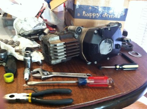 1981 Garelli Rally Sport - A disassembled engine part sits on a table surrounded by various tools, including a spark plug, wrench, and screwdrivers.