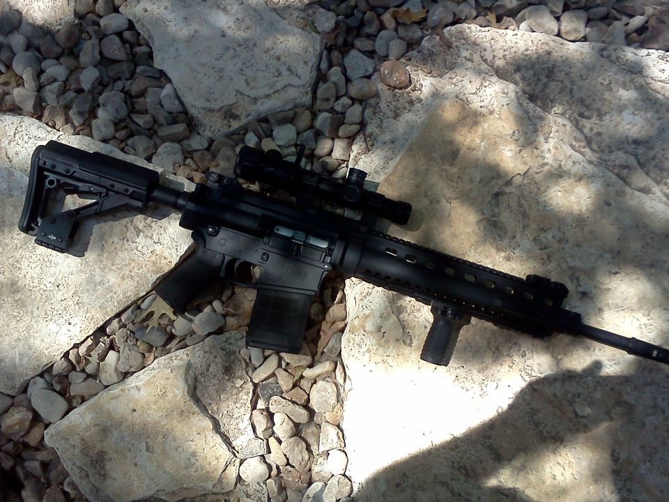 Assault rifle with scope and tactical grip on rocks