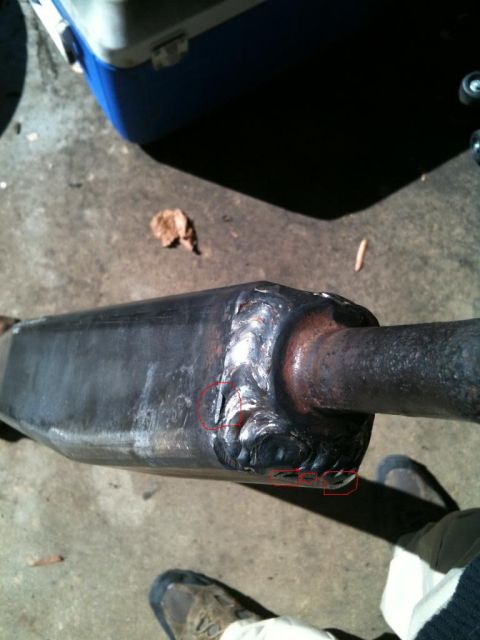 1992 Ford Bronco - Close-up of a welded exhaust pipe, with a cooler and a leaf visible on the ground.