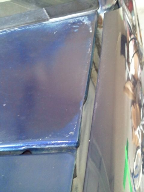 1994 Ford Bronco - Close-up of a blue car panel reveals wear and tear along its edge.