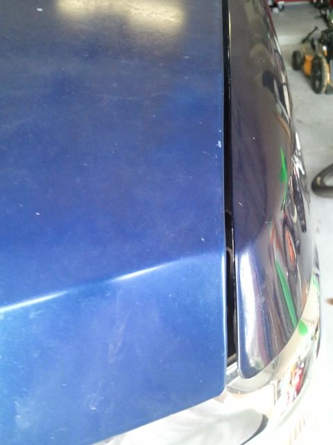 1994 Ford Bronco - Close-up view of the hood and fender seam on a blue vehicle, showing chrome trim.