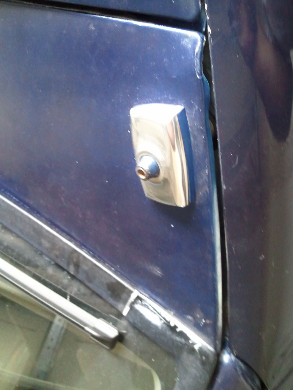Close-up of a blue car's door lock cylinder and trim piece