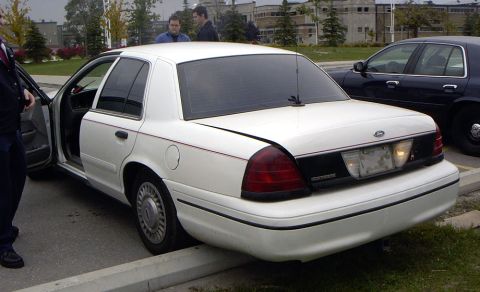 1999 Ford Crown Victoria - Rear view of a white Ford Crown Victoria sedan with its driver's door ajar.
