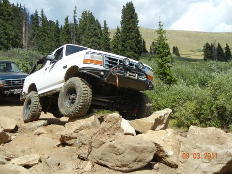 1996 Ford Bronco - A white SUV navigates a rocky trail with another vehicle in the background.